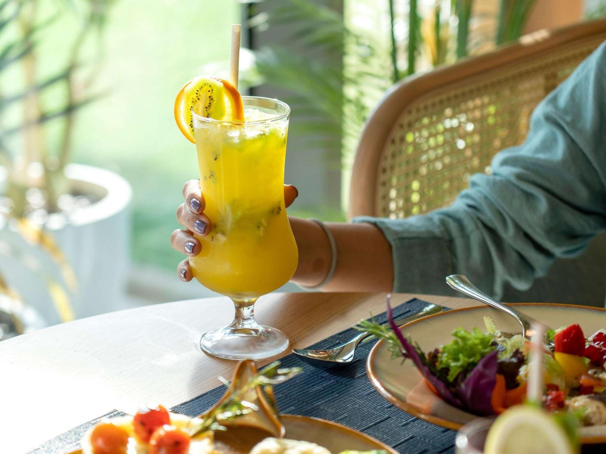 Swissotel Living Jiddah Esterno foto A woman holding a glass of juice